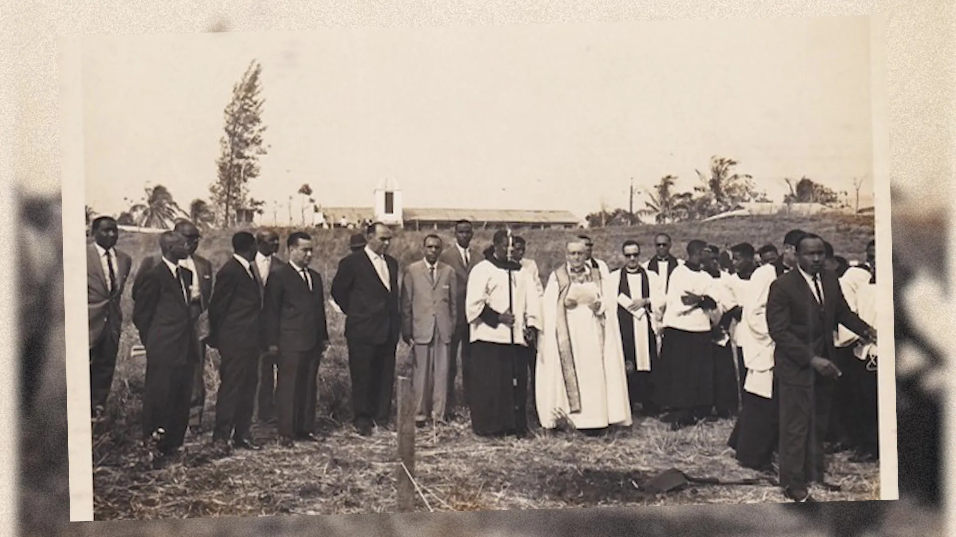 Fotografía histórica de un grupo de miembros y líderes eclesiásticos reunidos en un terreno.