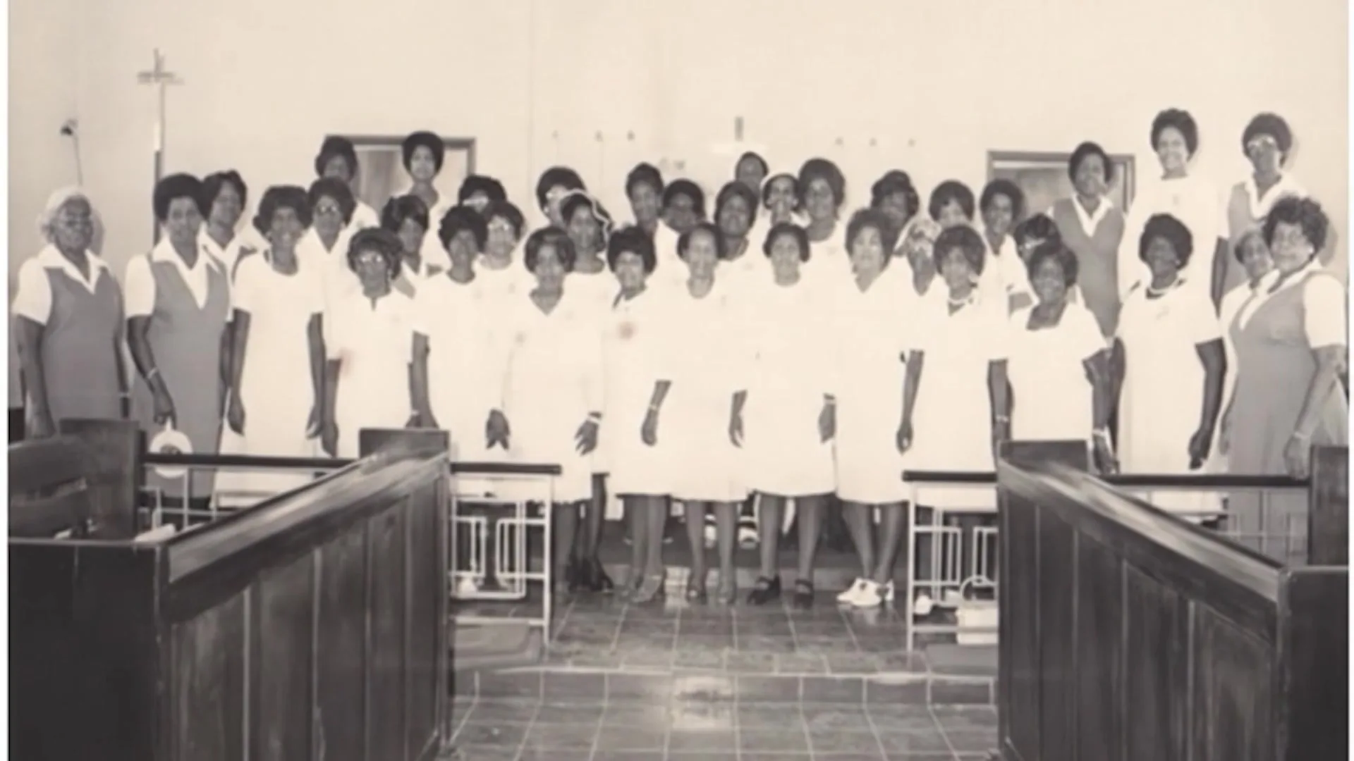 Fotografía histórica de mujeres de la congregación con uniformes blancos dentro del templo.
